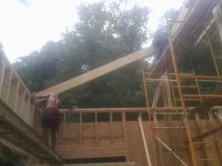 Carpenter raising a rafter beam on a new second story frame in Norwich