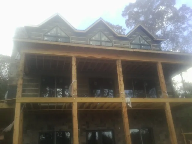 Dormers and porch framing on a large log home under construction — Roof Coating work by our crew in Norwich